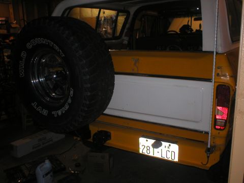 1978 Ford Bronco - The rear of a yellow and white SUV, a spare tire mounted on the tailgate and a license plate.