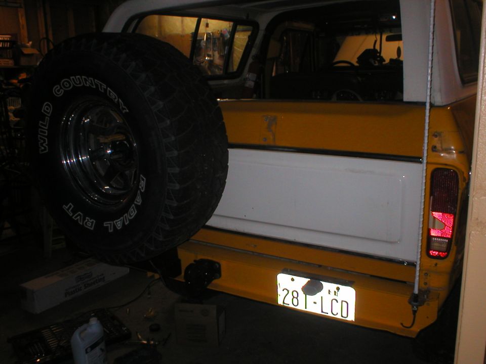 Rear bumper and spare tire of a yellow and white SUV