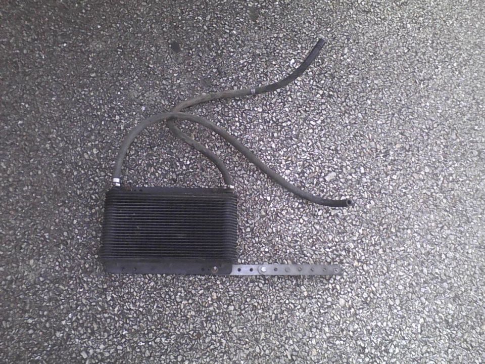 Oil cooler with three hoses attached, lying on asphalt