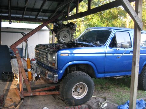 1994 Ford Bronco - A blue Ford Bronco, likely from the early 1980s, is undergoing engine removal with the help of an engine hoist.