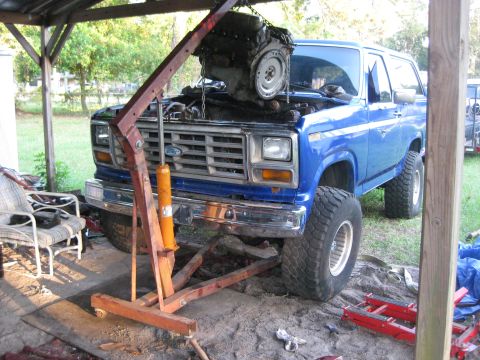 1994 Ford Bronco - A blue 1980 Ford Bronco is shown with its engine being removed using an engine hoist.
