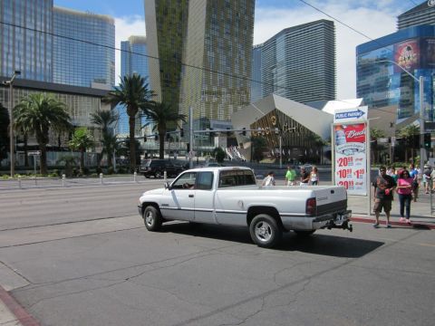 1991 Ford LTD Crown Victoria - A white Dodge Ram pickup truck drives through an intersection in Las Vegas, with modern buildings in the background.
