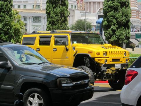 1991 Ford LTD Crown Victoria - A bright yellow Hummer H2 is parked on a street, partially obscured by other vehicles.