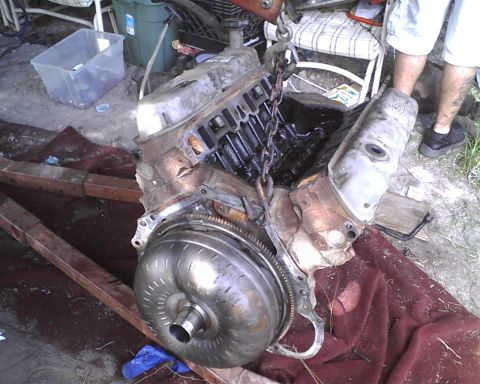 1985 Ford Bronco - An engine and torque converter assembly is being worked on, with a person visible in the background.
