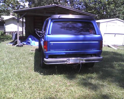 1985 Ford Bronco - The rear view of a blue SUV shows a trailer hitch and a small sticker on the back window.