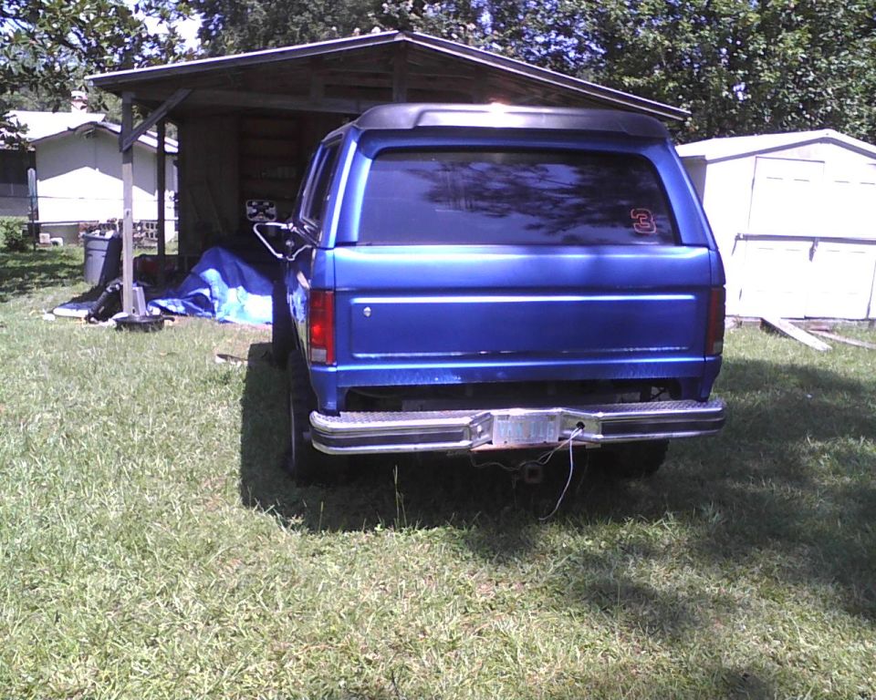 Blue SUV parked in front of a shed. Has a number 3 sticker on the rear window