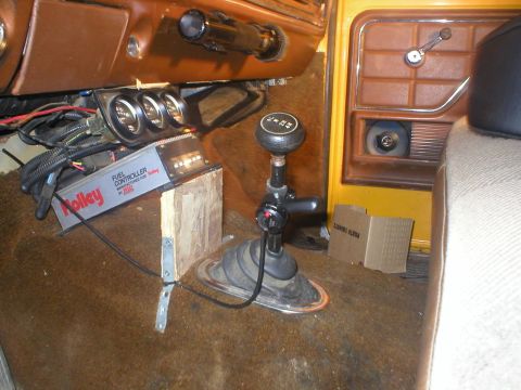 1978 Ford Bronco - The interior of a vehicle features a shifter, aftermarket gauges, and a Holley fuel controller mounted on the floor.
