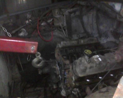 1985 Ford Bronco - Engine bay with an engine hoist attached to the engine, suggesting removal or installation.
