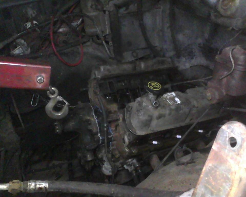 Engine bay with engine hoist hook attached to engine block. Supermotors.net logo visible