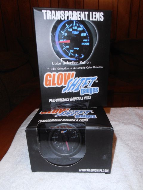 1990 Ford Bronco - Boxes of GlowShift performance gauges and pods are displayed, one with a boost gauge and the other with a voltage gauge.
