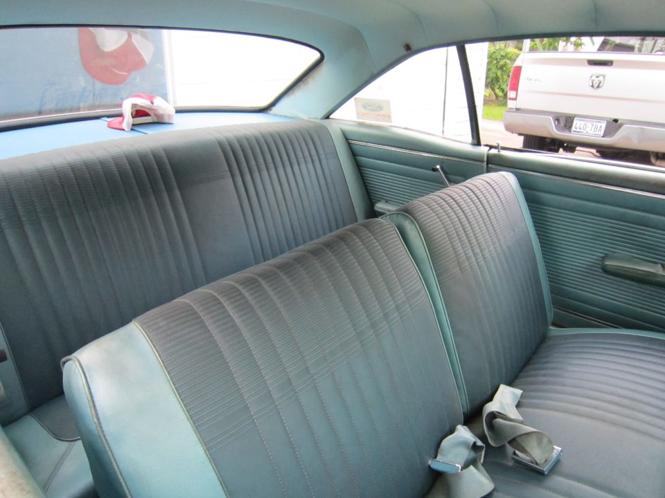Aqua blue vinyl bench seats and door panels inside a 1967 Ford Fairlane, seat belt on rear seat