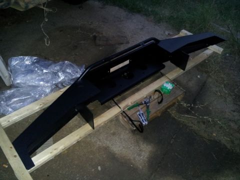 1986 Ford Bronco - Aftermarket front bumper assembly, likely for an SUV or truck, is displayed on wooden planks.
