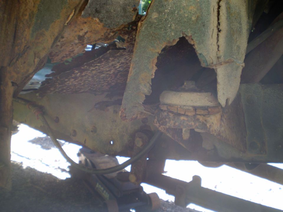 heavily rusted frame and suspension components of an old truck