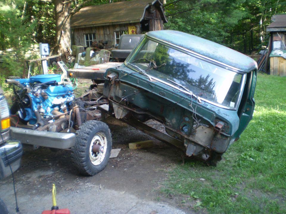 Green truck cab and chassis with a blue engine, viewed from the front-right. The vehicle is in a state of disrepair