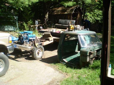 1979 Ford Bronco - Truck parts are laid out in a yard with a shed and trees in the background.