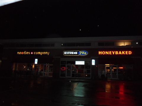 1989 Ford Bronco - Three businesses are visible at night, with illuminated signs and reflections on the wet ground.