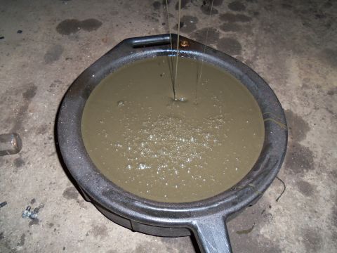 1989 Ford Bronco - Dirty oil is collected in a drain pan during an oil change.