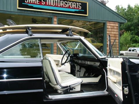 1964 Ford Galaxie - Interior view of a black 1964 Ford Galaxie 500XL, white upholstery and surfboards mounted on the roof rack.