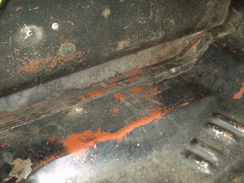 1964 Ford Galaxie - The undercarriage of a vehicle shows signs of rust and wear, with patches of orange paint visible.