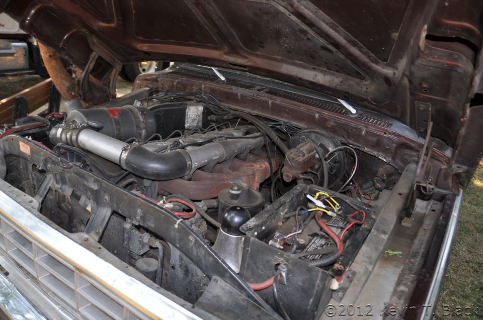 Truck engine bay with V8 engine, air intake, battery, and brake fluid reservoir visible