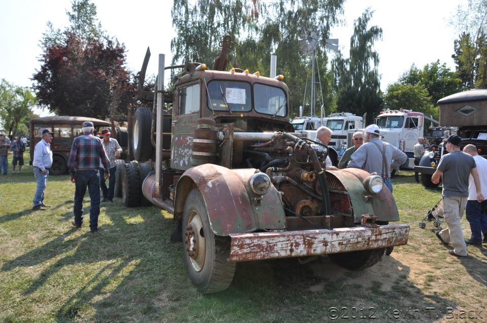 Rusty green truck with exposed engine, seen from the front