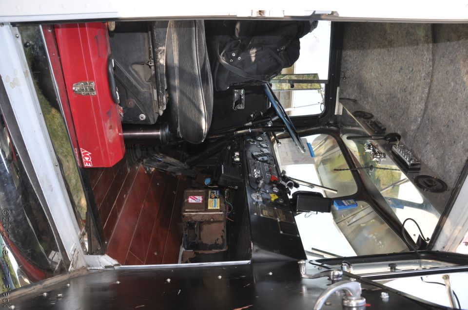 Truck interior with wooden floor, red toolbox, and dashboard with gauges