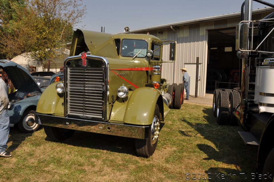 1959 Kenworth W900A semi-truck, hood open, parked on grass next to another truck