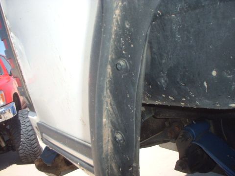 1991 Ford Bronco - Close-up view of a vehicle's fender flare and wheel well, with another truck partially visible.