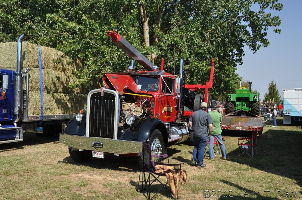 1959 Kenworth W900A tow truck with hood open, showing engine. Another truck and tractor are visible