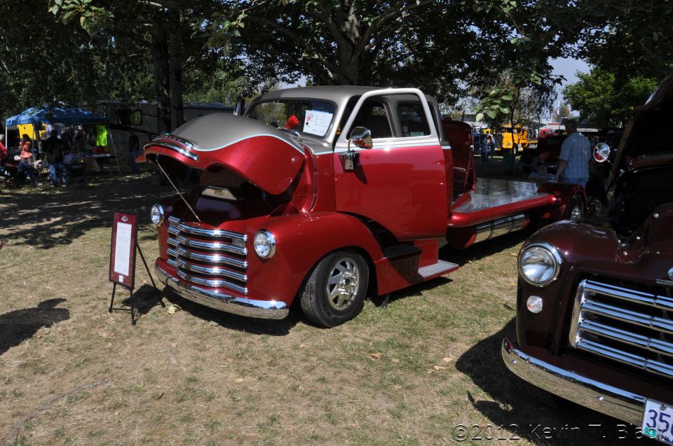 Red and silver flatbed truck with hood open, parked outdoors