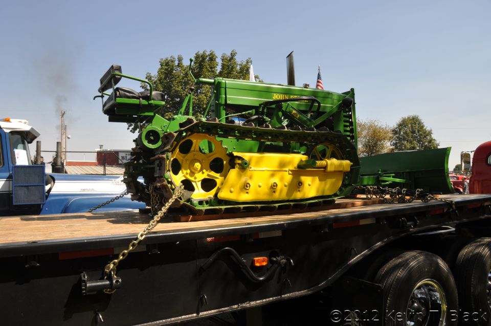 Green and yellow John Deere crawler tractor on a flatbed trailer