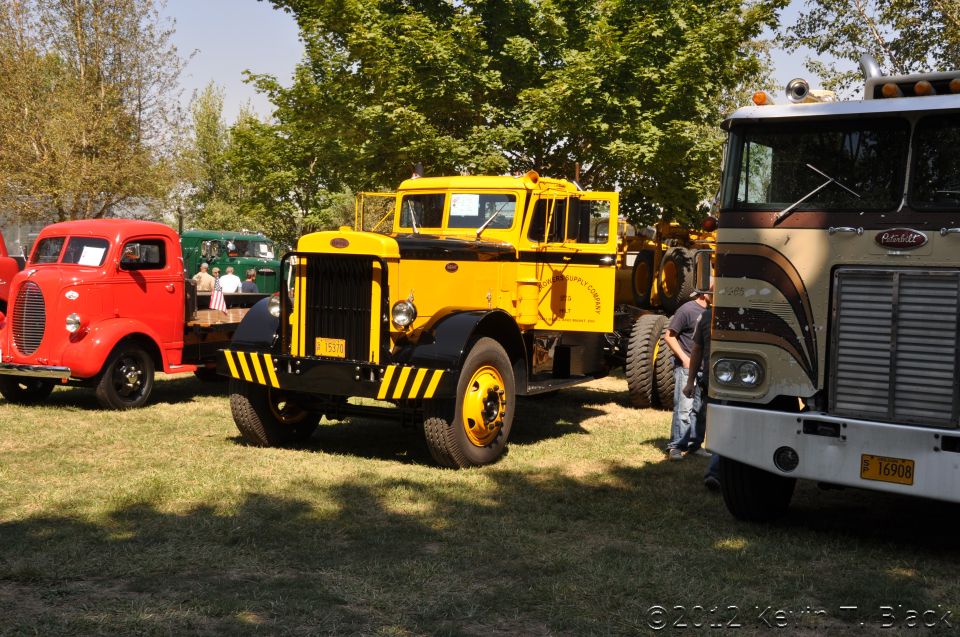 Yellow and black truck with a red truck and a brown truck nearby