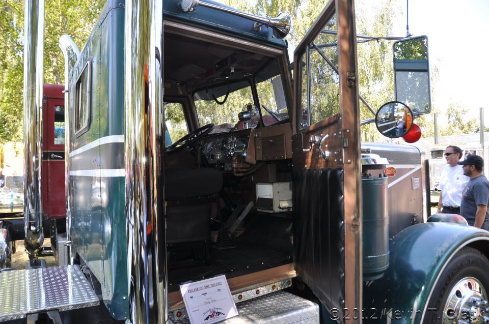 Interior of green and brown semi-truck cab, door open. Sign reads 'Please Do Not Touch'