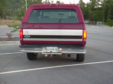 1993 Ford Bronco - Rear view of a maroon Ford Bronco with a distinctive silver and black stripe on its tailgate.