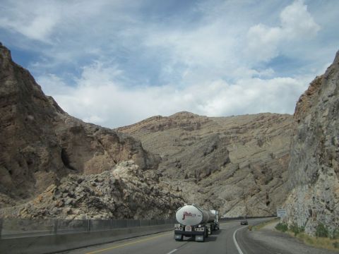1991 Ford LTD Crown Victoria - A tanker truck drives down a highway through a mountainous landscape under a cloudy sky.