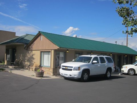 1991 Ford LTD Crown Victoria - A white SUV is parked in front of a motel building on a sunny day. Another vehicle is partially visible to the right.