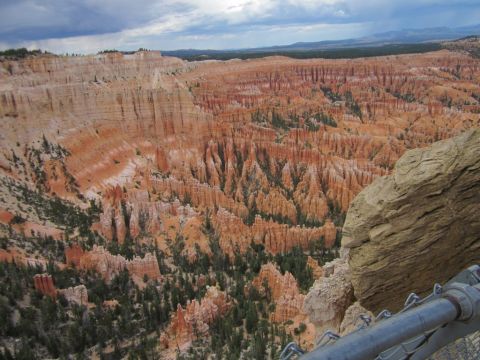 1991 Ford LTD Crown Victoria - A vast landscape of orange rock formations and pine trees under a dramatic sky at Bryce Canyon National Park.