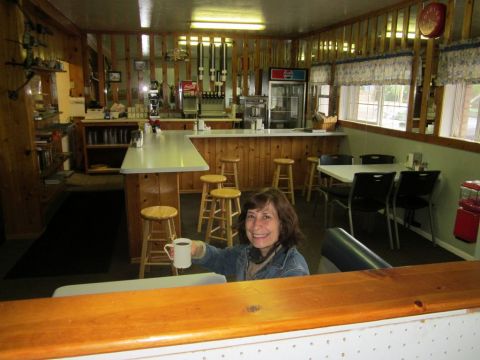 1991 Ford LTD Crown Victoria - Interior view of a diner, showing a woman with a coffee mug at the counter.