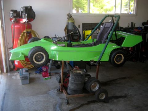 1996 Ford Bronco - A bright green go-kart is elevated on a stand in a garage, surrounded by tools and equipment.