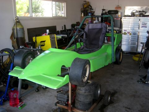 1996 Ford Bronco - A bright green go-kart sits in a cluttered garage, ready for assembly or repair.