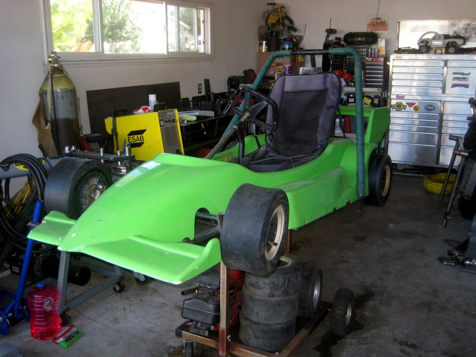 Green go-kart with racing tires on a stand in a garage