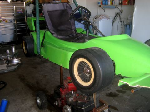 1996 Ford Bronco - A bright green go-kart is shown in a garage setting, supported by a stand with its engine exposed.