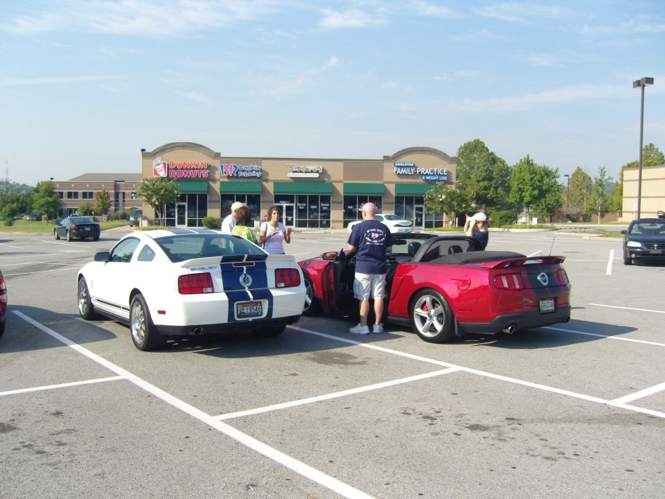 2007 Ford Mustang coupe with blue stripes and red convertible Mustang parked in a lot