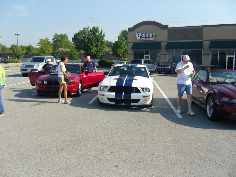 White 2007 Ford Mustang with blue racing stripes parked in a lot