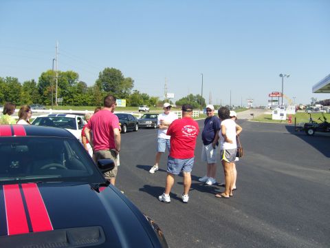 2007 Ford Mustang - Several people gather around cars at an outdoor event on a sunny day.