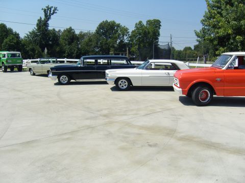 2007 Ford Mustang - Several vintage vehicles are lined up outdoors on a sunny day.