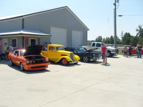 2007 Ford Mustang - Several vehicles are parked outside a building on a sunny day, with people milling around.