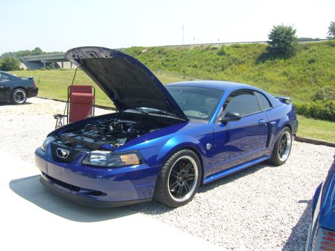 2007 Ford Mustang - A blue coupe with its hood open sits on a gravel lot next to a black car.