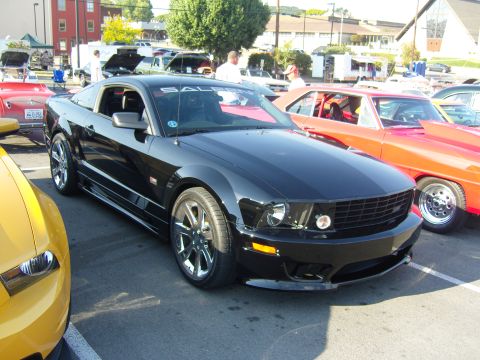 2007 Ford Mustang - A black Ford Mustang is parked at a car show, with other vehicles visible in the background.