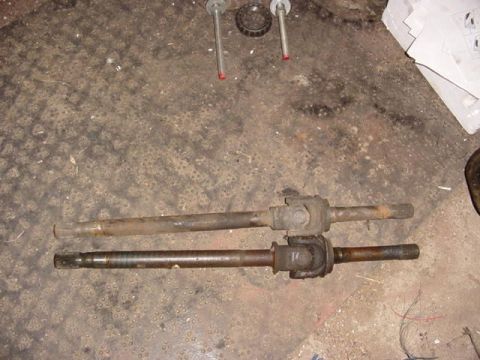 1992 Ford Bronco - Two drive shafts are laid out on a dirty concrete floor, with some tools and papers in the background.
